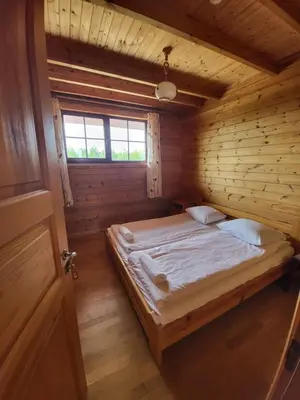 a bedroom with a bed in a wooden cabin at Vytauto kaimas - Didelis namas in Aukštadvaris
