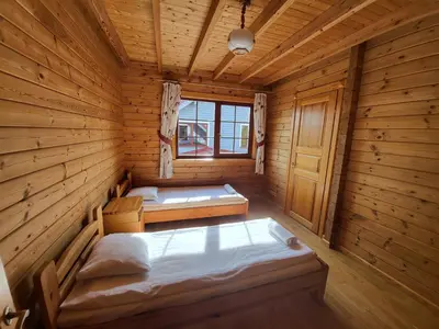 a room with two beds in a wooden cabin at Vytauto kaimas - Didelis namas in Aukštadvaris