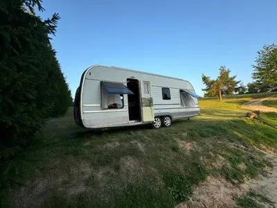 a silver caravan parked on a grass field at Mobilus namelis su jacuzi kubilu prie ezero Birvarelax in Kariotiškės