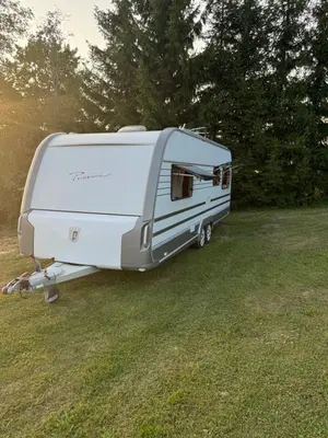 a white trailer parked in a grass field at Mobilus namelis su jacuzi kubilu prie ezero Birvarelax in Kariotiškės