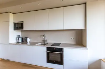 a kitchen with white cabinets and a sink at DRUSKININKŲ PANORAMA Apartamentai in Druskininkai