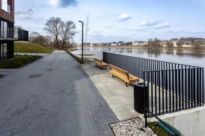 a walkway with two benches next to a river at Nemunaiciai Riverside Suites in Aleksotas
