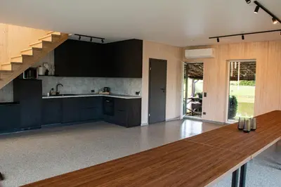 a kitchen with black cabinets and a wooden table at Sodyba Divaiva in Anykščiai