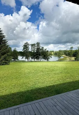 a grassy field with trees and a body of water at Kaštonų krantas in Antotylʼtse