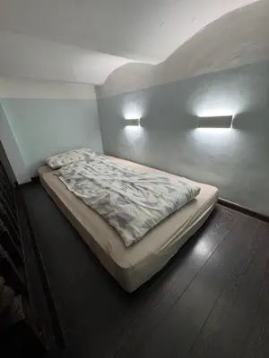 a bed in a room with two lights on the wall at BOSTONA Flat in Vilnius