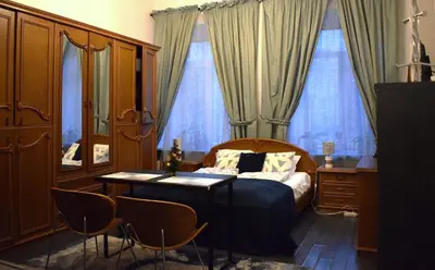 a bedroom with a bed and a table with chairs at BOSTONA Flat in Vilnius