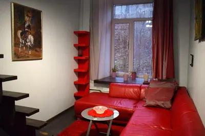 a living room with a red couch and a window at BOSTONA Flat in Vilnius