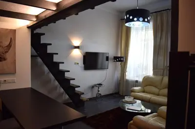 a living room with a staircase and a tv at BOSTONA Flat in Vilnius
