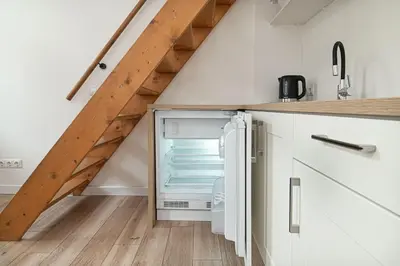 an open refrigerator in a kitchen under a staircase at Lovely Loft in Old Town with free parking by URBAN RENT in Vilnius