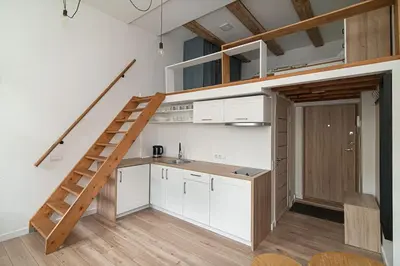 a kitchen with white cabinets and a staircase in a loft at Lovely Loft in Old Town with free parking by URBAN RENT in Vilnius