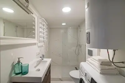 a white bathroom with a sink and a shower at Lovely Loft in Old Town with free parking by URBAN RENT in Vilnius