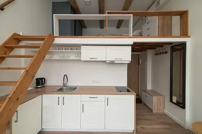 a kitchen with white cabinets and a loft bed at Lovely Loft in Old Town with free parking by URBAN RENT in Vilnius