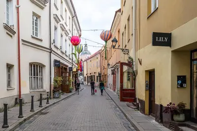 two people walking down a street with buildings at Classic Apartments In The Prestigious Stikliu Str by Reside Baltic in Vilnius