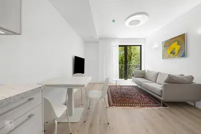 a white living room with a table and a couch at Bright 2BR with Private EV Parking, workspace, AC in Kaunas