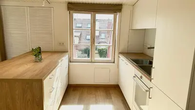 a kitchen with white cabinets and a large window at City Center Appartment in Vilnius