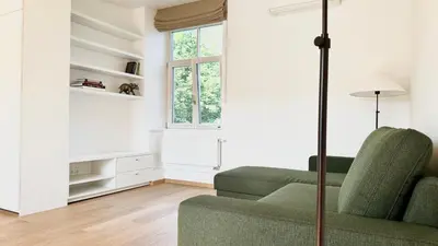 a living room with a green couch and a window at City Center Appartment in Vilnius