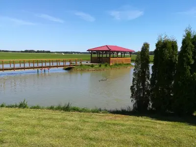 a bridge over a body of water with a gazebo at Poilsio namai Aerodromas in Bajorai