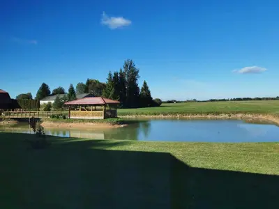 a pond with a gazebo in the middle of a field at Poilsio namai Aerodromas in Bajorai