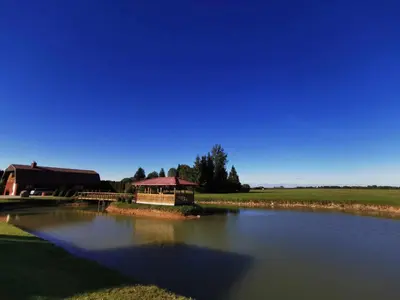 a pond with a gazebo next to a building at Poilsio namai Aerodromas in Bajorai