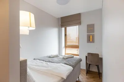 a white bedroom with a bed and a window at Stylish Simplicity - 1BDR Cozy Stay in Vilnius in Kontverki
