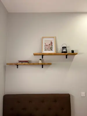 a wall with two wooden shelves above a couch at Bastion Apartment Old Town in Vilnius