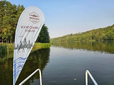 a paddle board in the water next to a lake at Vilos NEMUNO SLĖNIS namukai in Birštonas