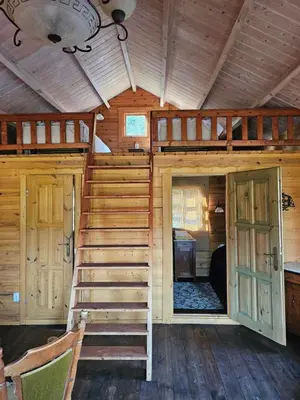 a wooden cabin with a staircase in a room at Vilos NEMUNO SLĖNIS namukai in Birštonas