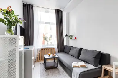 a living room with a gray couch and a window at The K1A Studio Collective in Vilnius