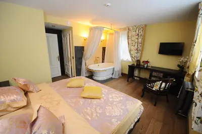 a bedroom with two beds and a bathroom with a tub at Argo Trakai in Trakai