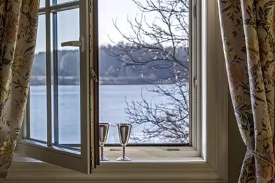 two glasses sitting on a window sill looking out at the water at Argo Trakai in Trakai