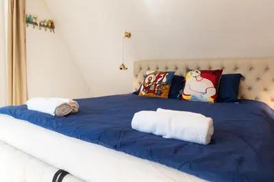 a bed with blue and white sheets and pillows at Vila Pušyno 4 in Kulautuva