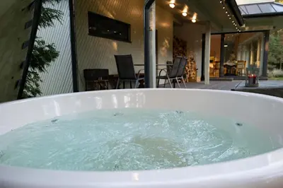 a bath tub filled with water next to a patio at Vila Pušyno 4 in Kulautuva