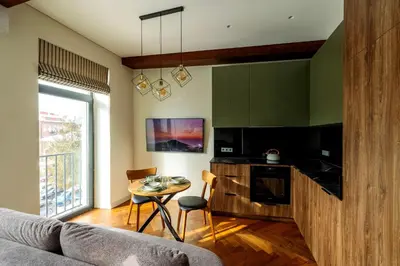 a living room with a table and a kitchen at Studio Nemuno 27 in Kaunas