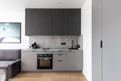 a kitchen with white and black cabinets and a couch at Hook Studios Vilnius Old Town in Vilnius