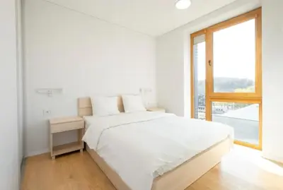 a white bedroom with a large bed and a window at Apartment with balcony and castle view by URBAN RENT in Vilnius