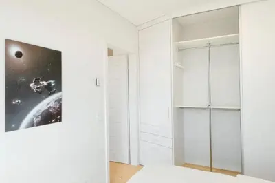 a white room with white cabinets and a picture on the wall at Apartment with balcony and castle view by URBAN RENT in Vilnius