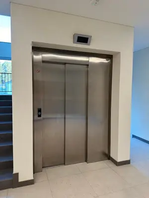 a metal elevator door in a building with stairs at Jaukus butas 2 kambariu girioje in Kaunas