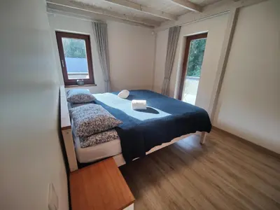 a bedroom with a bed with a blue blanket and two windows at River Mind Villa with SPA in Zalioji