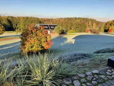 a view of a lake with a house in the background at Sporto ir poilsio centras KORNEALITA IEVALAUKIS in Gaveikėnai