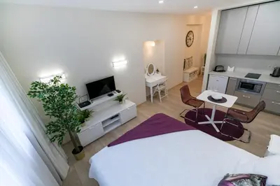 a bedroom with a bed and a table and a kitchen at Raugyklos apartamentai in Vilnius