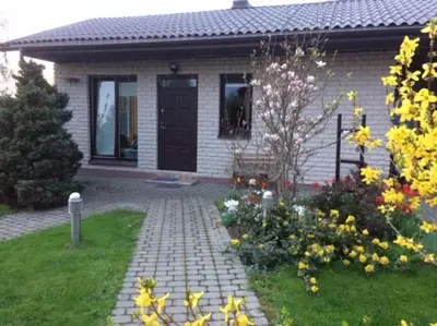 a house with a brick walkway and flowers in the yard at Cottage with fireplace and sauna in Pakalniškės