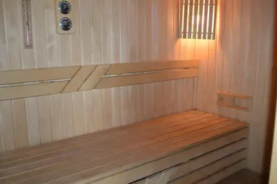 a wooden bench in a sauna with a light at Cottage with fireplace and sauna in Pakalniškės