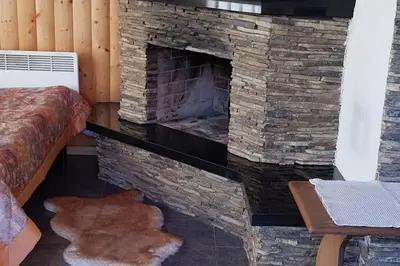 a stone fireplace in a room with a bed at Cottage with fireplace and sauna in Pakalniškės
