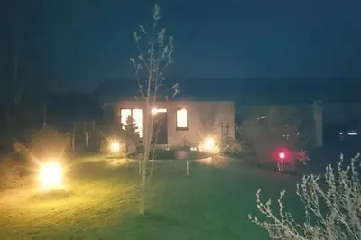 a house with lights in a yard at night at Cottage with fireplace and sauna in Pakalniškės