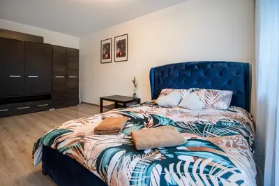 a bedroom with a bed with a blue head board at Urban Escape Kaunas - Quiet Apartment 5 km from City Center in Kaunas