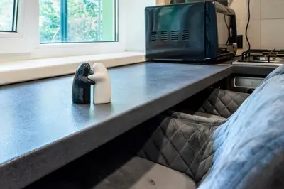 a bed in a room with a microwave and a pillow at Urban Escape Kaunas - Quiet Apartment 5 km from City Center in Kaunas