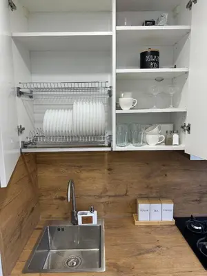 a kitchen with a sink and a shelf with dishes at Moncerat in Šiauliai