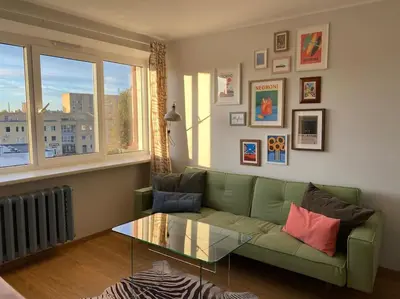 a living room with a green couch and a glass table at Cloud apartments in Alytus