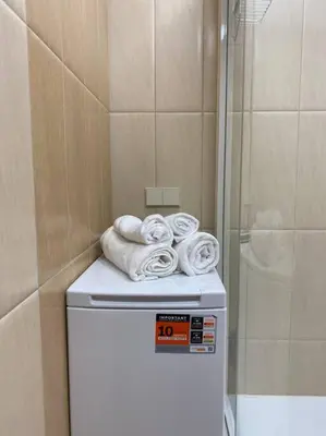 a pile of towels on top of a refrigerator in a bathroom at Cloud apartments in Alytus