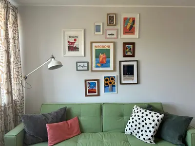 a living room with a green couch and pictures on the wall at Cloud apartments in Alytus